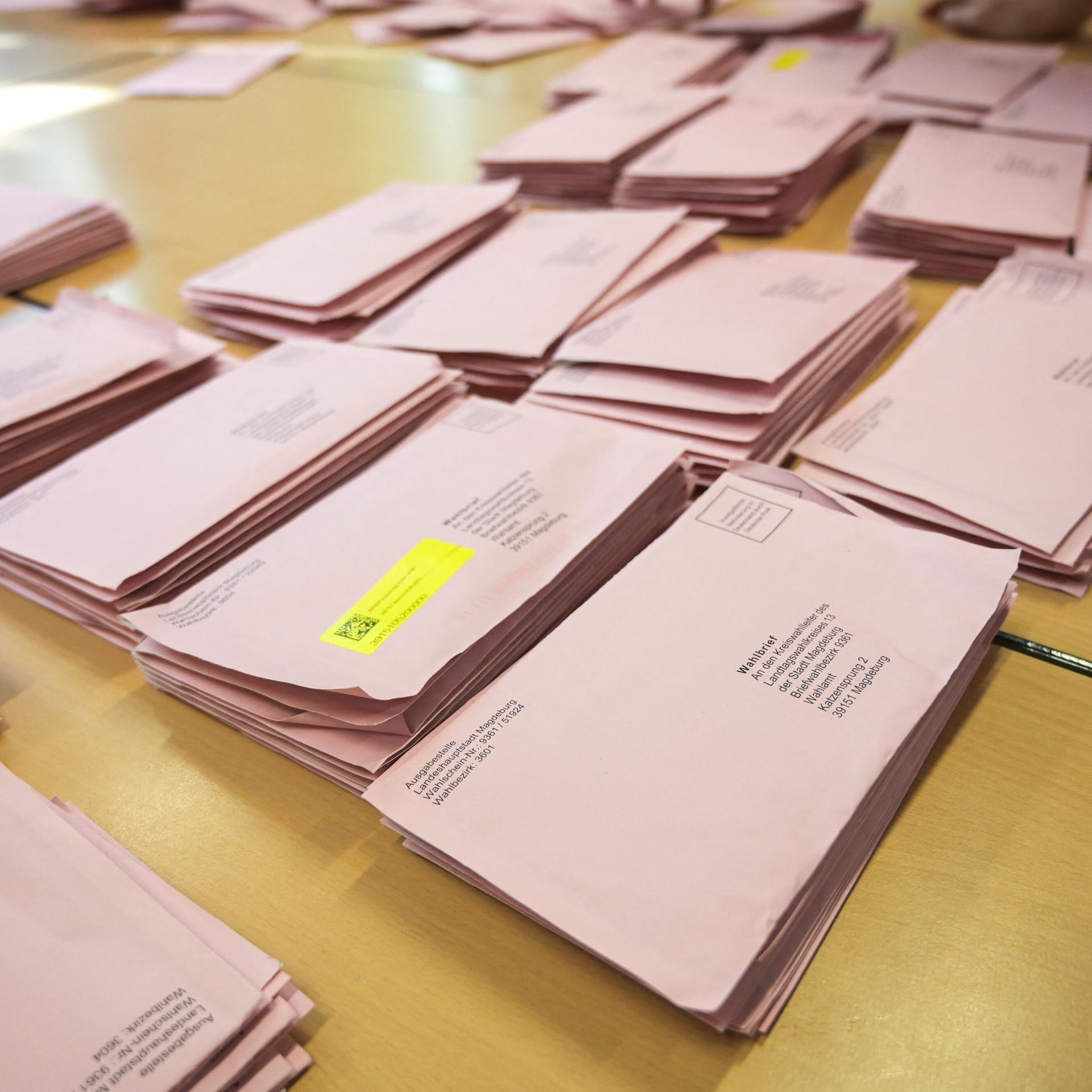 Briefwahlumschläge für die Landtagswahl in Sachsen-Anhalt liegen auf einem Tisch. 