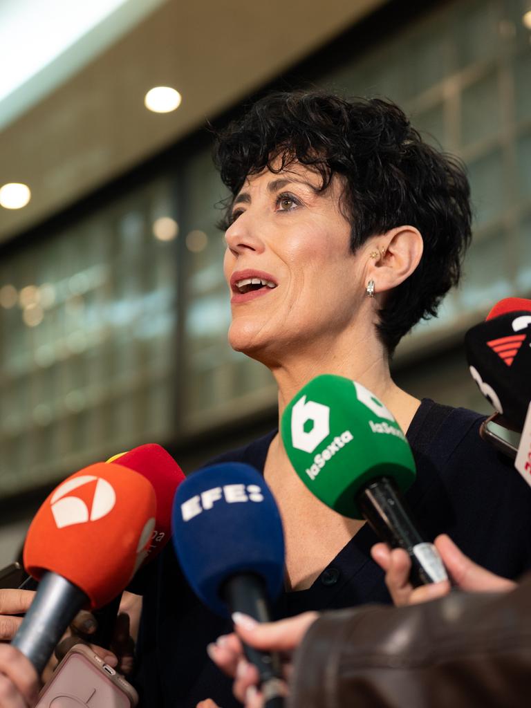 Elma Saiz steht zwischen Mikrofonen, umringt von Journalisten.