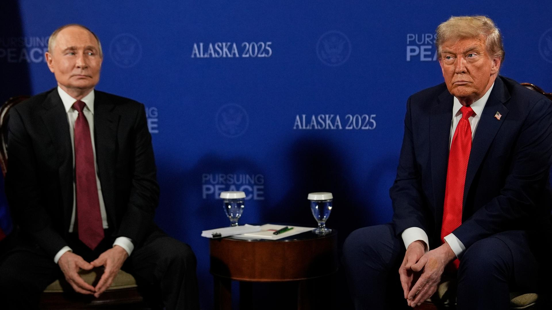 Trump und Putin blicken bei einer Pressekonferenz mit starren Minen. 