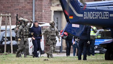 Eine verhaftete Person wird von der Bundespolizei zu einem Hubschrauber geführt. 