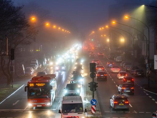 Dichter Verkehr auf einer innerstädtischen nächtlichen Straße im Nebel.