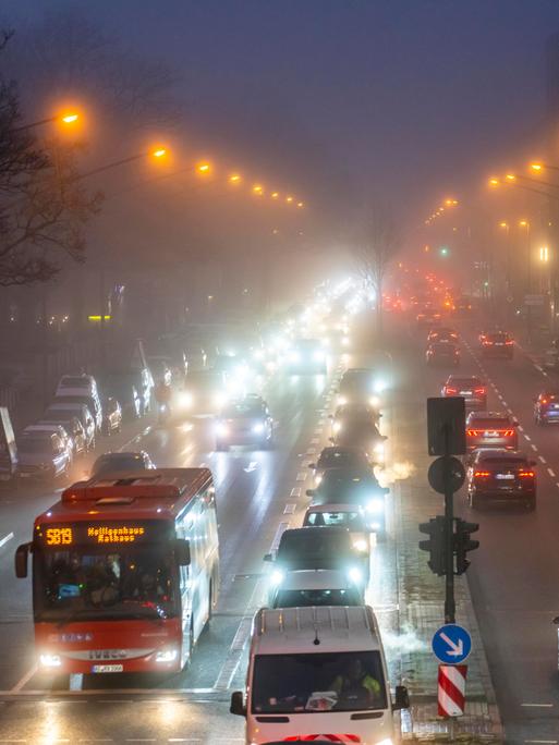 Dichter Verkehr auf einer innerstädtischen nächtlichen Straße im Nebel.