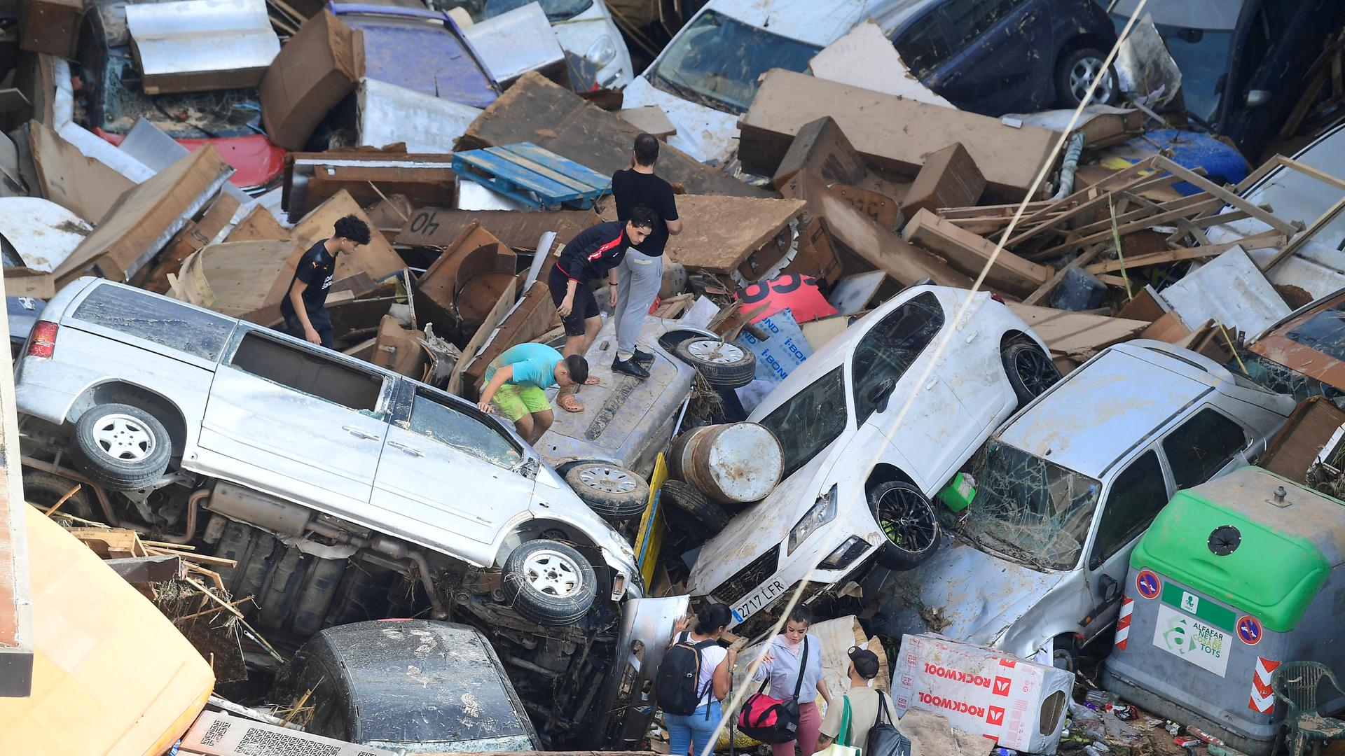 Persons climb on piled up cars following floods in Sedavi, south of Valencia, eastern Spain, on October 30, 2024.