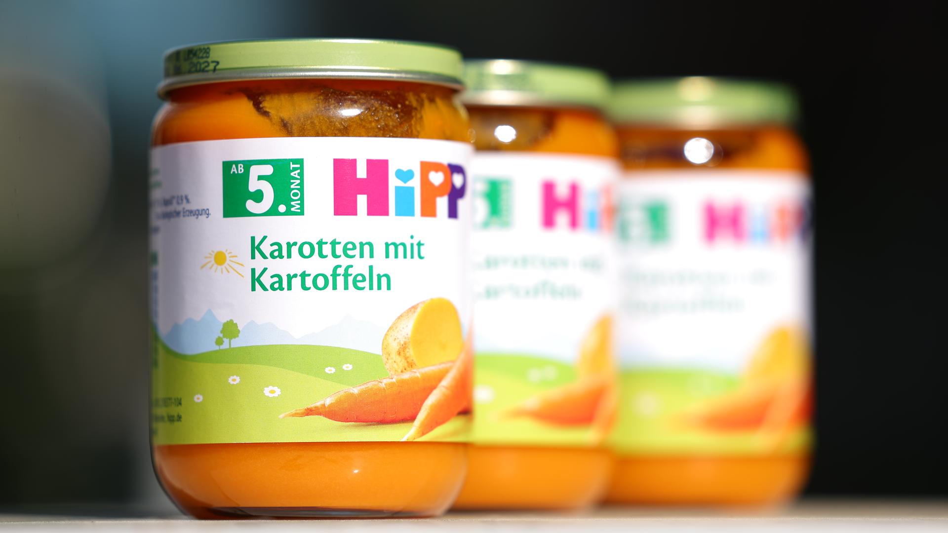 Auf einem Tisch stehen drei Artikel von der Sorte "Gemüsegläschen Karotte mit Kartoffeln" des Herstellers Hipp.