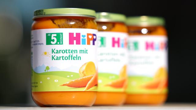 Auf einem Tisch stehen drei Gläser von der Sorte "Gemüsegläschen Karotte mit Kartoffel" des Herstellers Hipp.