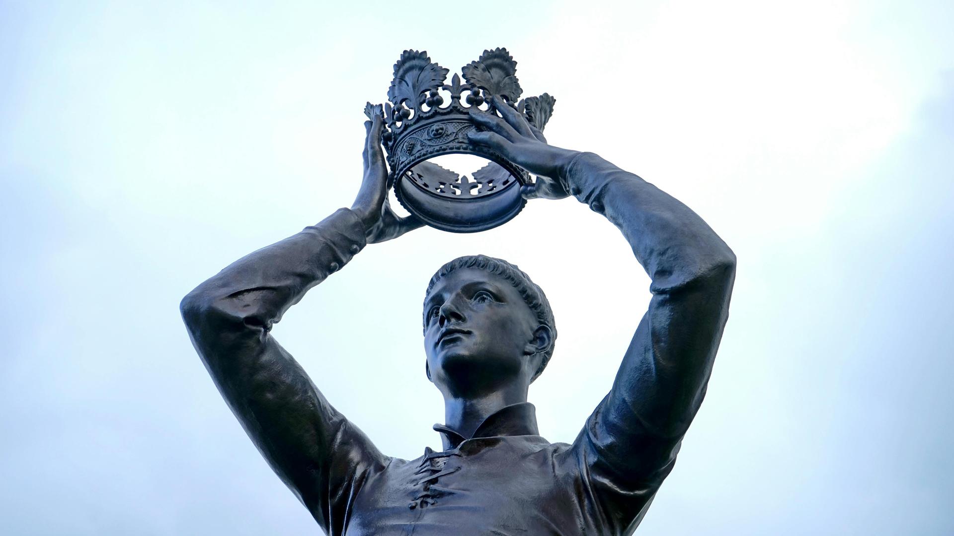 Eine Statue zeigt einen Mann, der sich eine Krone aufs Haupt hebt.