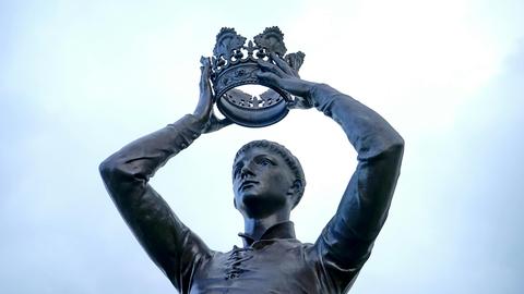 Eine Statue zeigt einen Mann, der sich eine Krone aufs Haupt hebt.