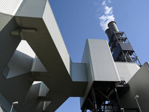 Ein Kühlturm ragt über einer komplexen Industrieanlage hervor. Ein Kühlturm ragt über einer komplexen Industrieanlage hervor.