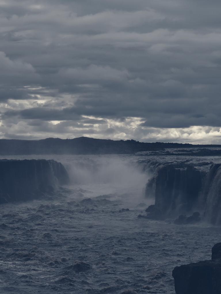 Der Wasserfall Hafragilsfoss in Gischt und Nebel, aufgenommen im August 2021. Darüber bricht die Sonne ganz leicht durch die Wolken.