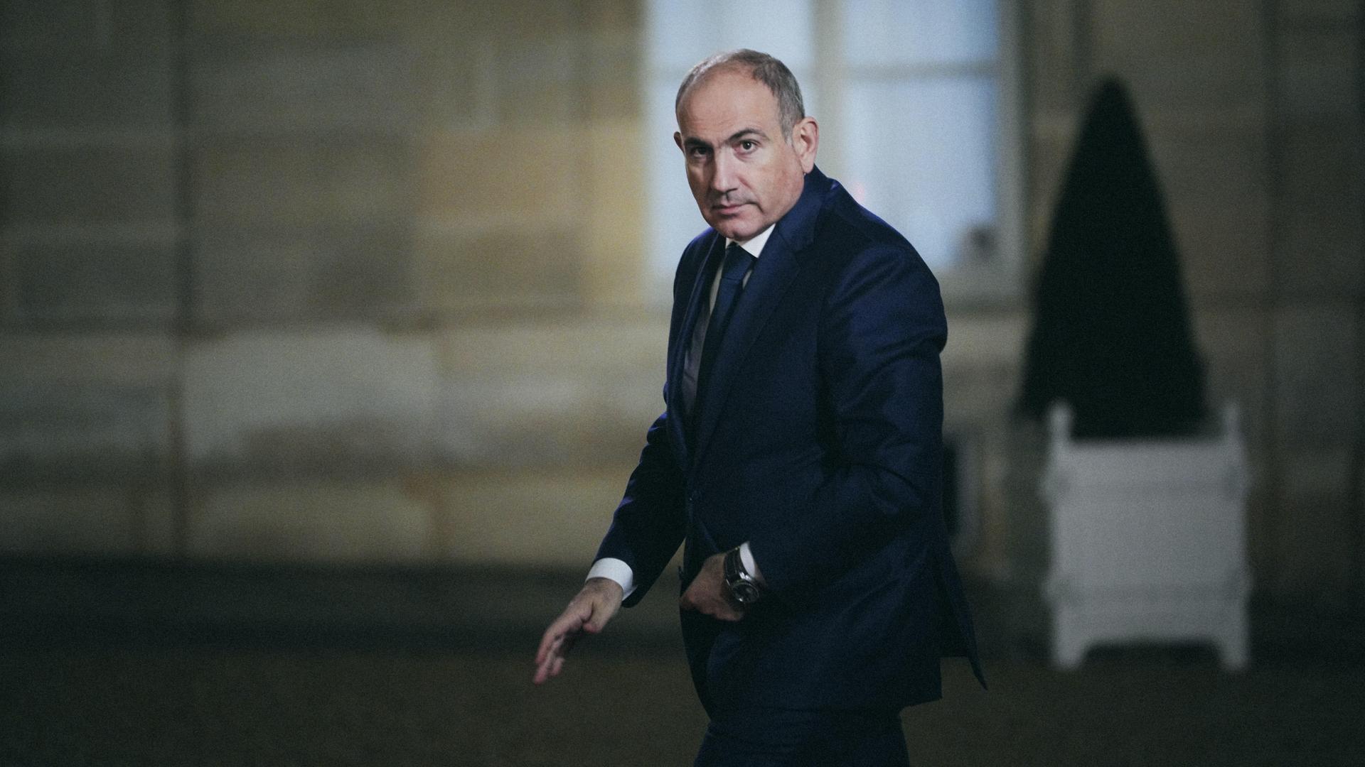 Der armenische Premierminister Pachinian knöpft sich im Gehen das Jackett zu.