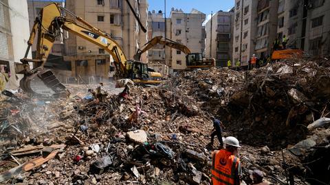 Bagger und Arbeiter an einem Schutthaufen zwischen mehrstöckigen Wohnhäusern in Beirut.