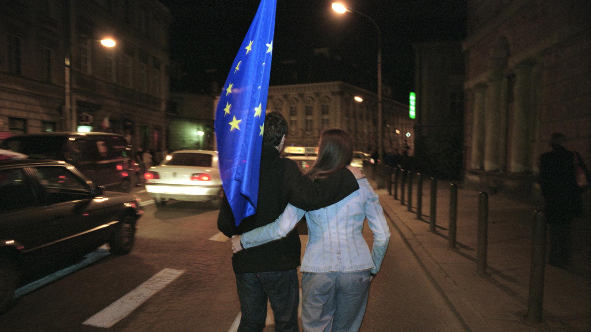01.05.2004, Warschau, Masowien, Polen - Ein junges Paar unterwegs mit einer Europa-Flagge. 