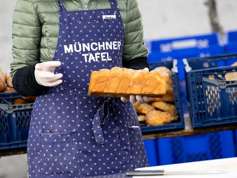 Eine Frau hält bei der Münchner Tafel ein Brot in der Hand 