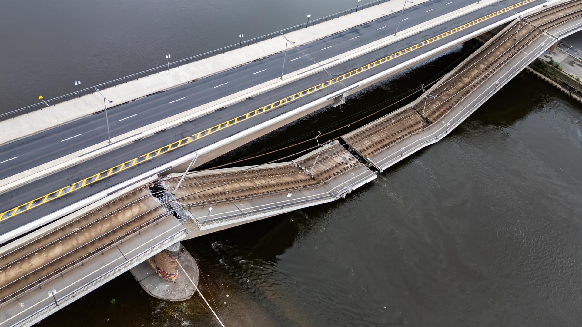 Teile einer Brücke sind in einen Fluss gestürzt. Der als Fahrbahn genutzte Teil ist intakt. Der als Schienenweg genutzte Teil ist eingebrochen.