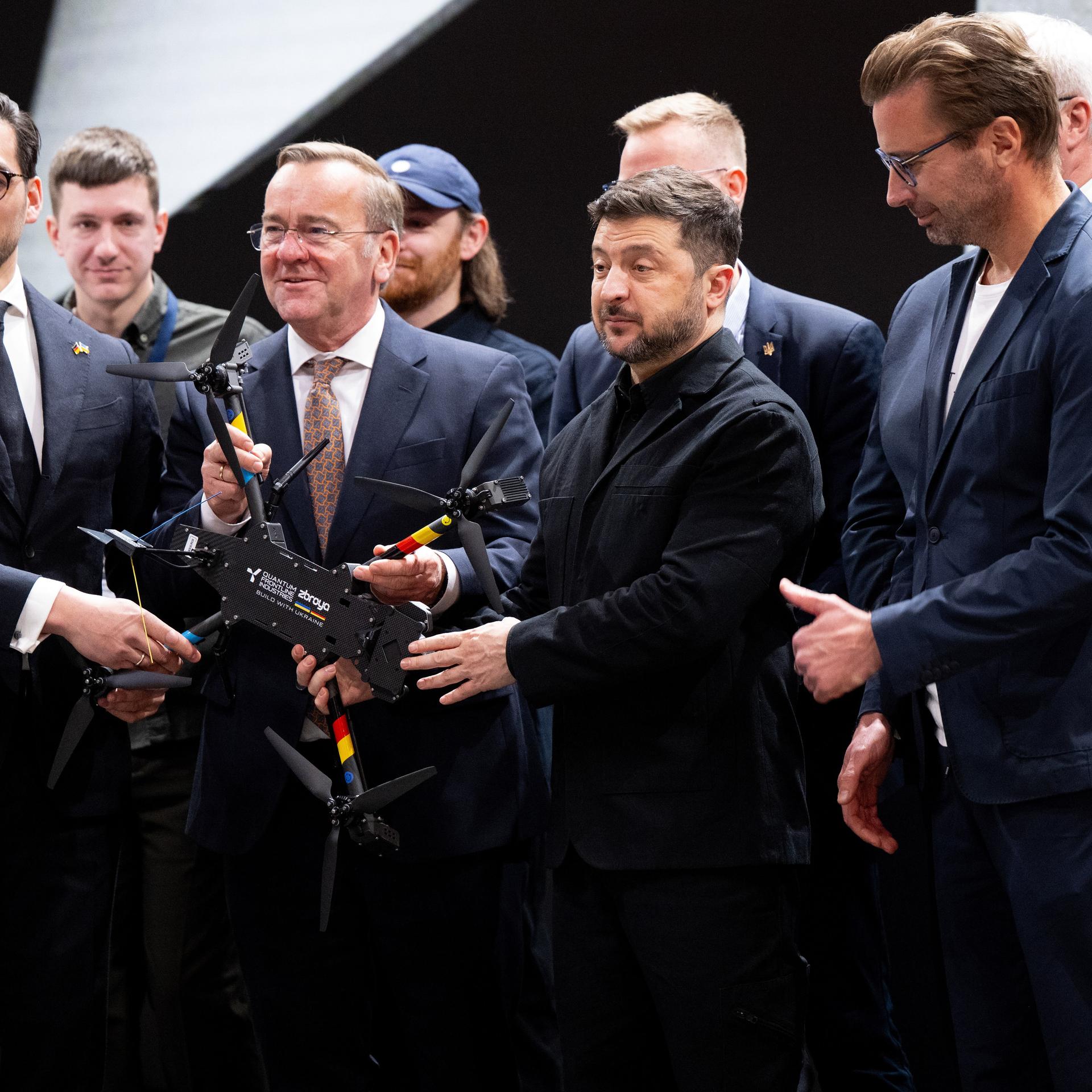 Wolodymyr Selenskyj (Mitte r), Präsident der Ukraine, und Boris Pistorius (Mitte l, SPD), Verteidigungsminister, besuchen vor Beginn der Münchner Sicherheitskonferenz den Drohnenhersteller Quantum Frontline Industries. Das deutsch-ukrainische Gemeinschaftsunternehmen soll Drohnen für die Streitkräfte der Ukraine im Krieg gegen Russland produzieren.