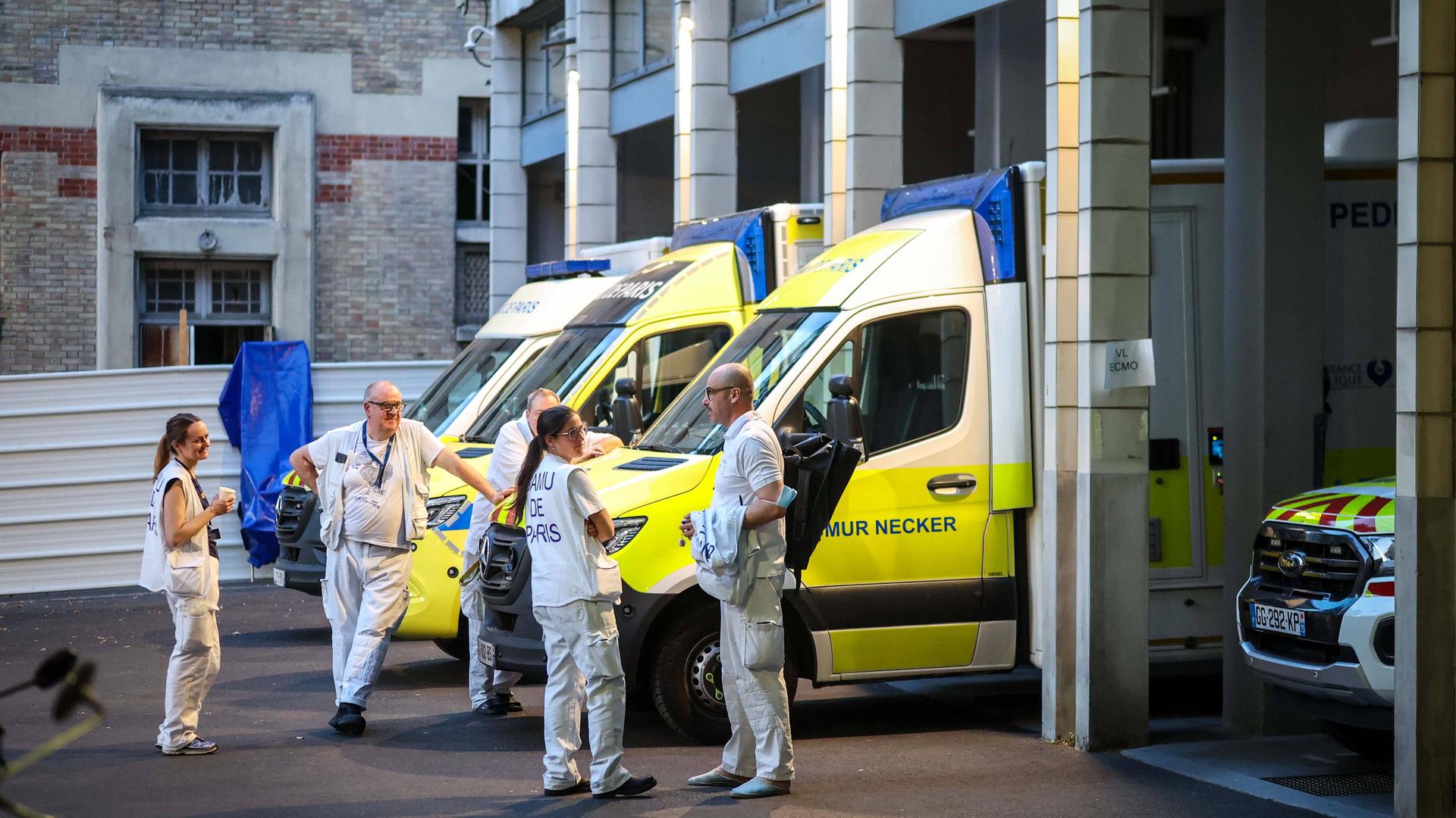 SAMU 75-Mitarbeiter stehen vor gelb-weißen Rettungswagen und unterhalten sich. SAMU 75-Mitarbeiter stehen vor gelb-weißen Rettungswagen und unterhalten sich.