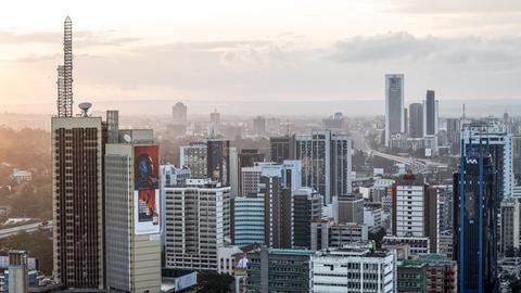 Zu sehen ist eine Luftaufnahme von Nairobi. Im Vorder- sowie im Hintergrund stehen mehrere Hochhäuser. Dazwischen schlängelt sich eine Straße.