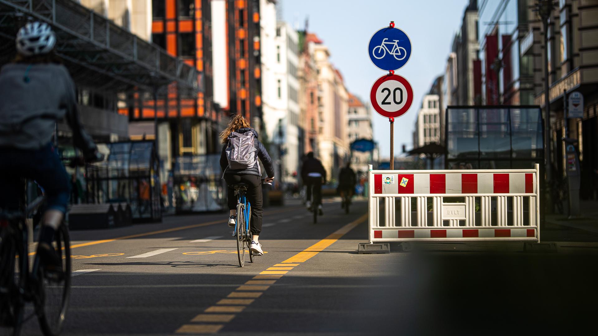Fahrradfahrer in der Berliner Friedrichstraße und ein Schild, das eine Geschwindigkeitsbegrenzung auf 20 Stundenkilometer anzeigt. Fahrradfahrer in der Berliner Friedrichstraße und ein Schild, das eine Geschwindigkeitsbegrenzung auf 20 Stundenkilometer anzeigt.