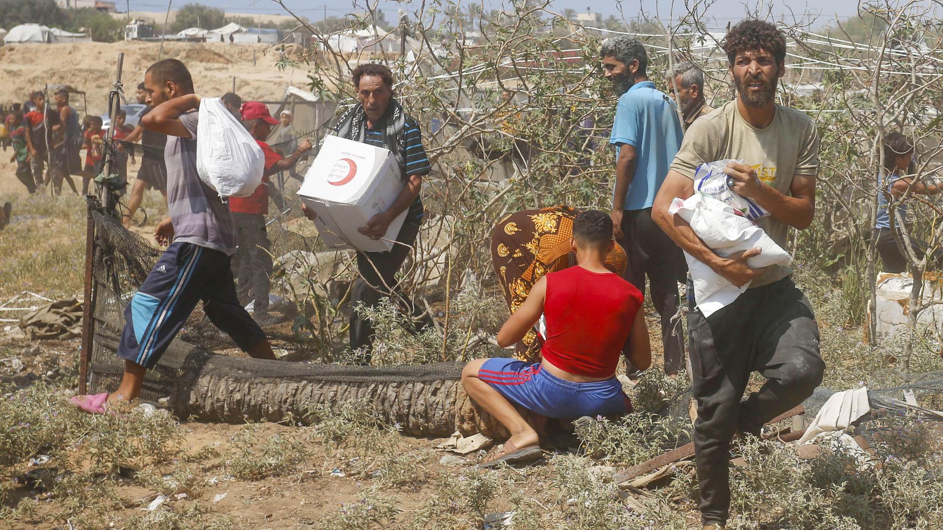 Palästinensische Männer tragen Hilfspakete, die aus der Luft über Gaza abgeworfen wurden. 
