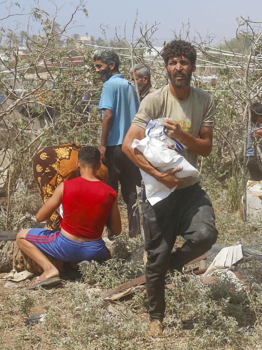 Palästinensische Männer tragen Hilfspakete, die aus der Luft über Gaza abgeworfen wurden. 