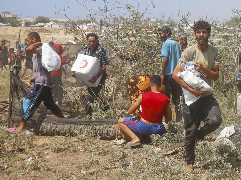 Palästinensische Männer tragen Hilfspakete, die aus der Luft über Gaza abgeworfen wurden. 