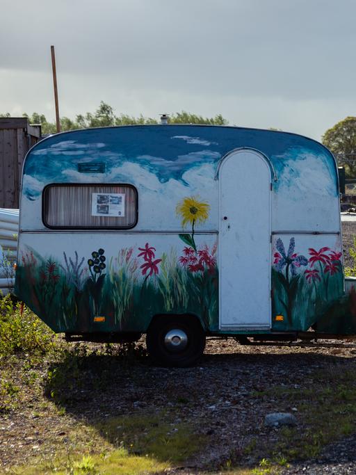 Ein kleiner Wohnwagen steht vor einem Hostel 