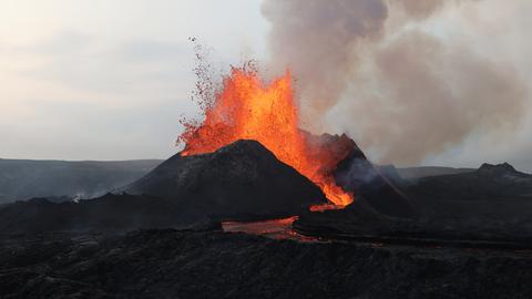 Ein Vulkanausbruch, die Lavawolke steigt auf und läuft am Berg herunter.