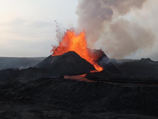 Ein Vulkanausbruch, die Lavawolke steigt auf und läuft am Berg herunter.