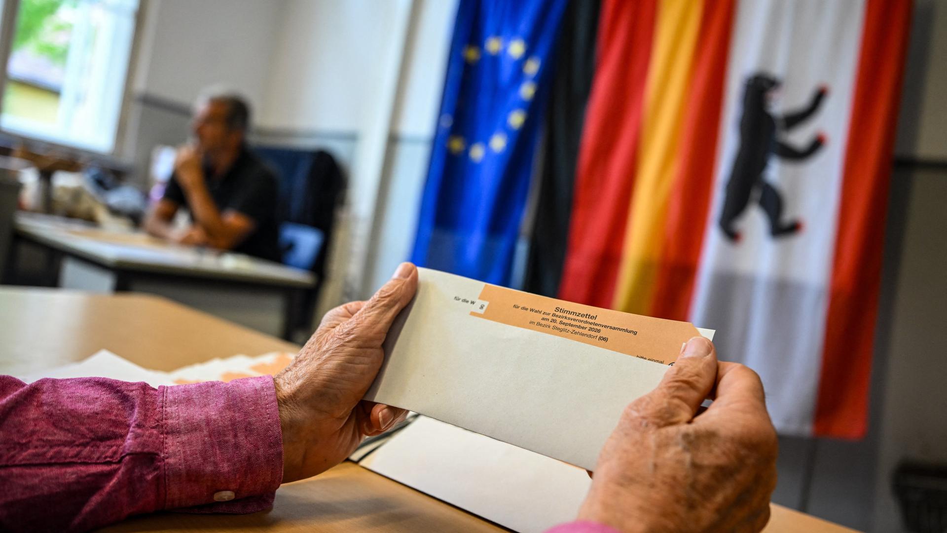 Eine Wahlhelferin hält einen Stimmzettel in einem Wahlumschlag in einem Wahllokal in der Hand