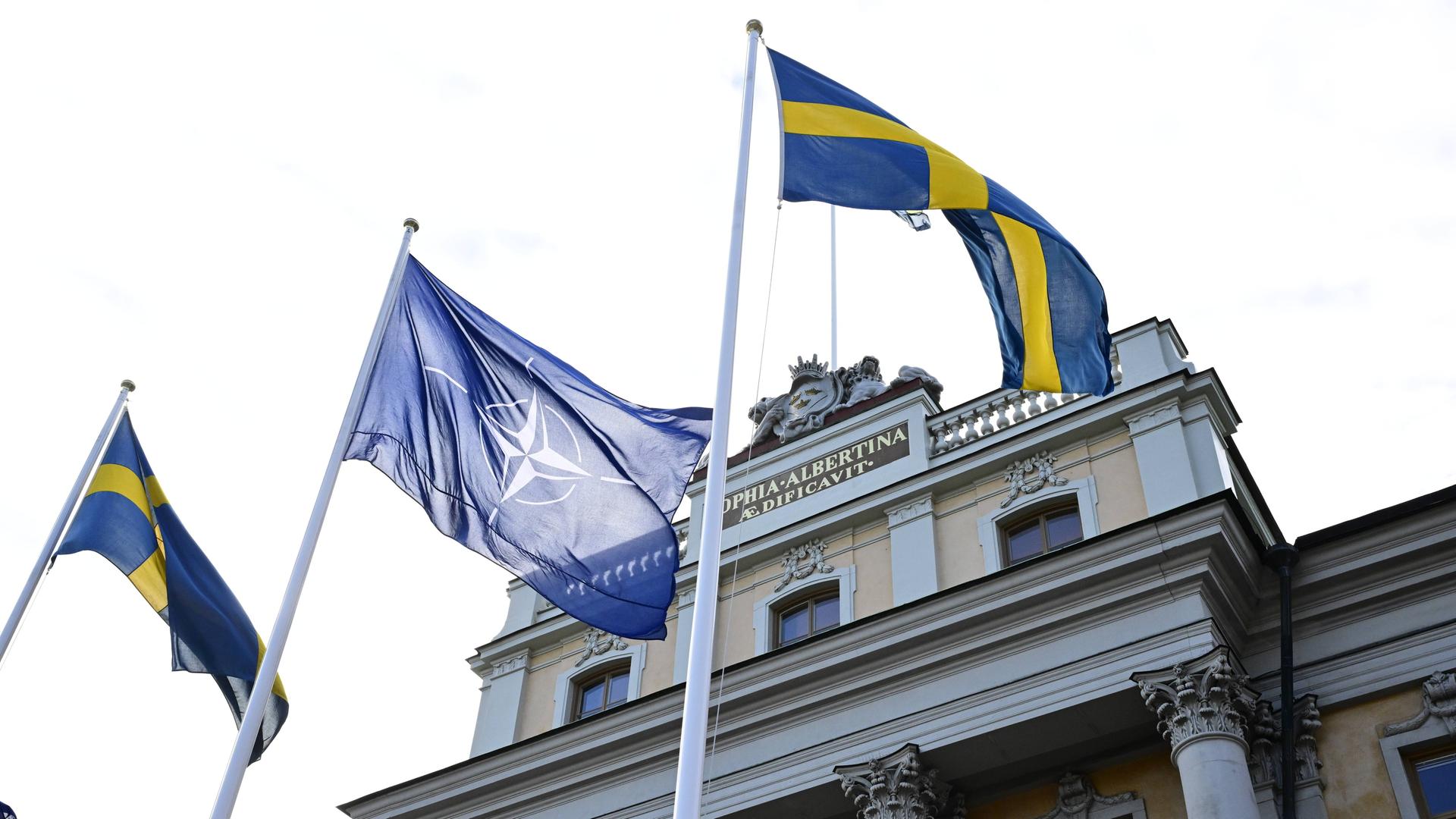 Die Flagge der Nato zwischen zwei schwedischen Flaggen in Stockholm.