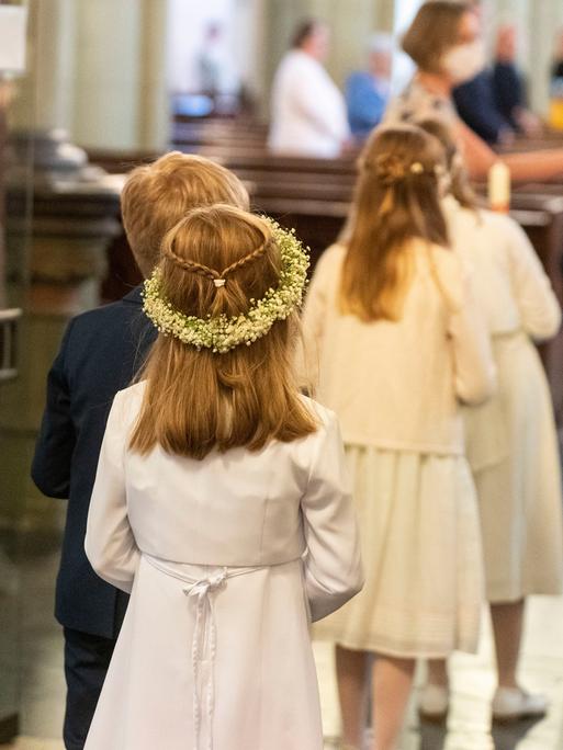 Kinder kommen in die Kirche zur Erstkommunion.