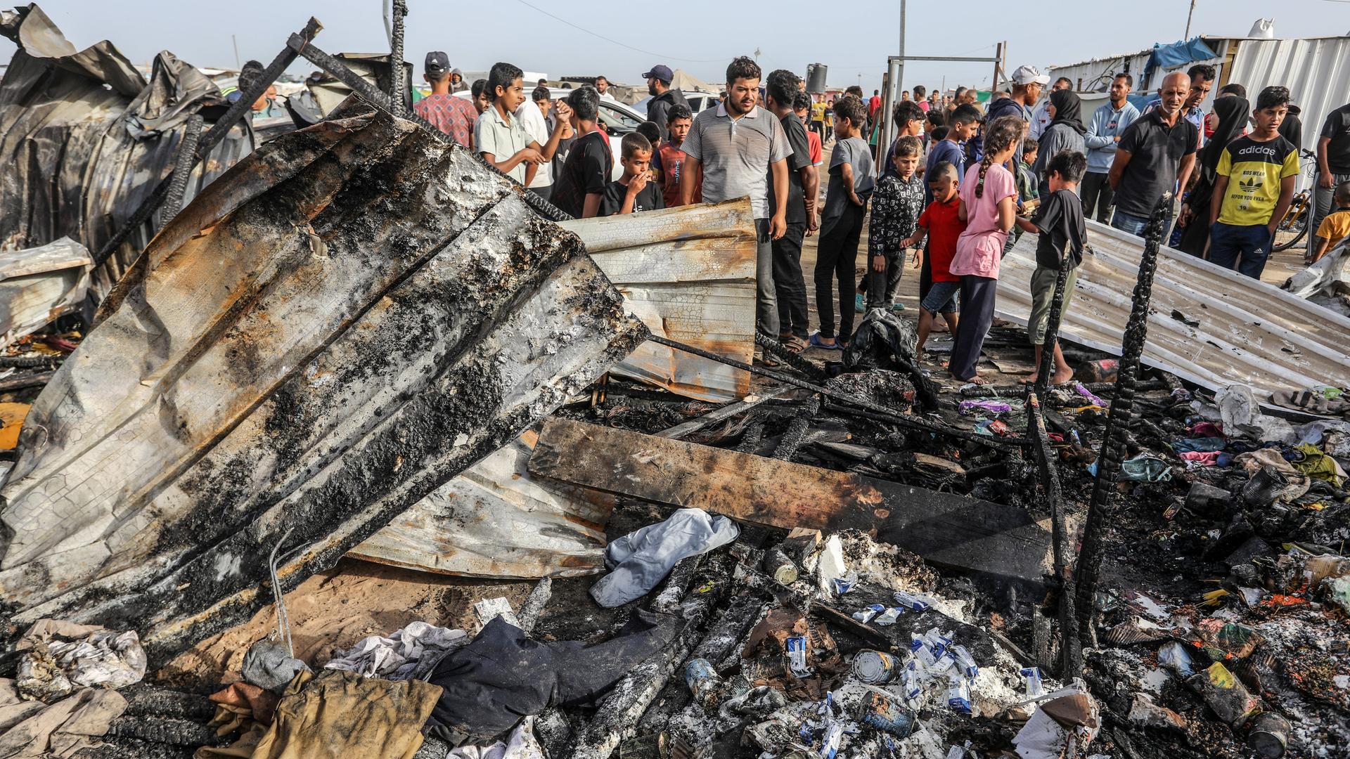 Mehrere Palästinenser stehen Trümmern und zerstörten Zelten, die bei einem israelischen Luftangriff auf Rafah getroffen worden waren. 
