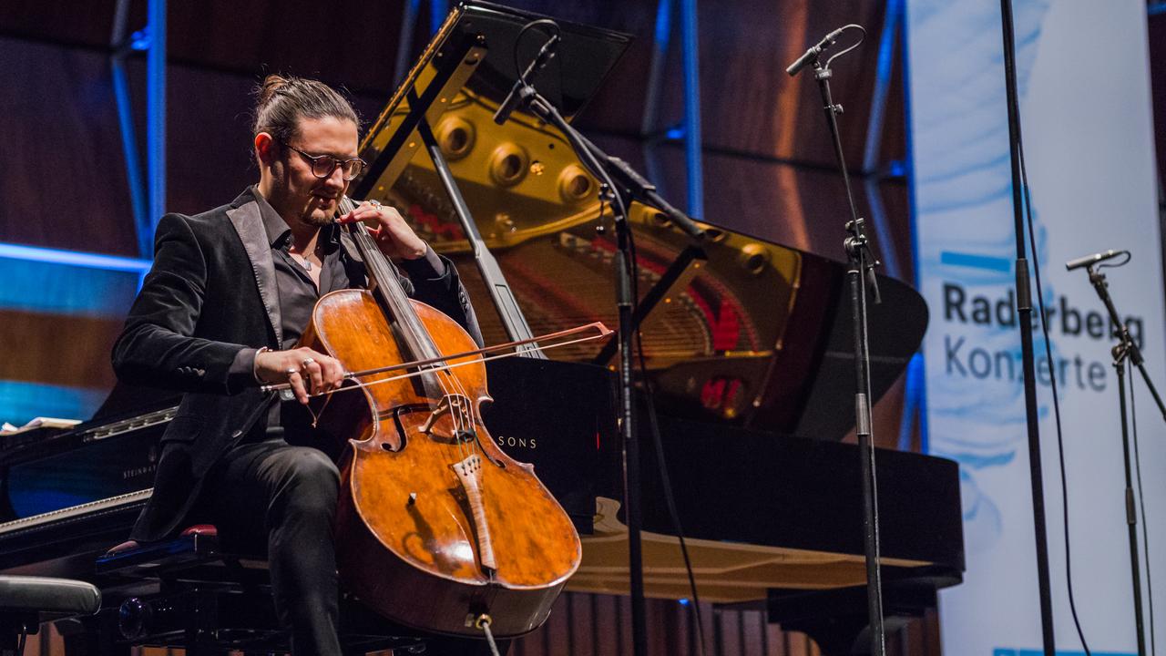 Santiago Cañón-Valencia sitzt mit seinem Violoncello auf der Bühne und spielt beim Raderbergkonzert ein Solowerk.