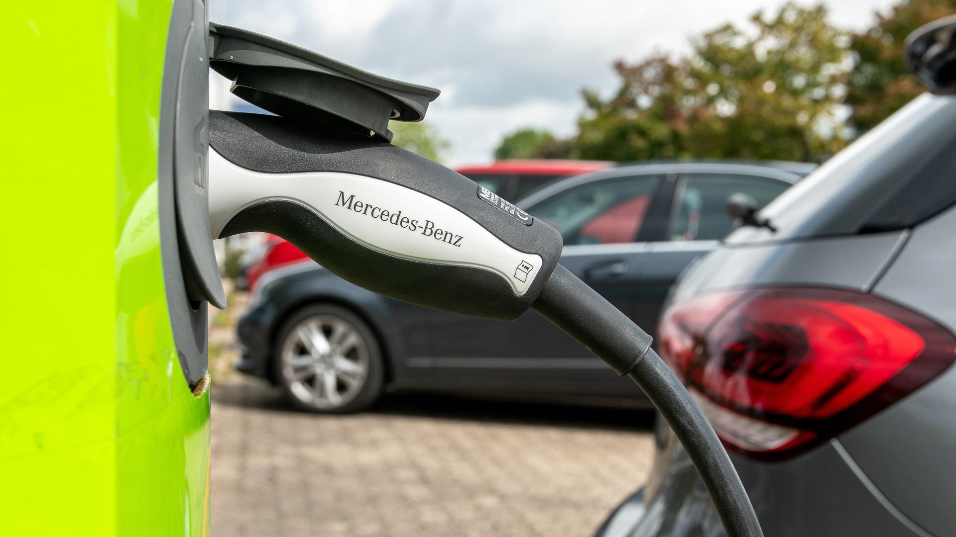 Ein Ladestecker mit der Aufschrift Mercedes-Benz steckt in einer Ladesäule für Elektroautos.