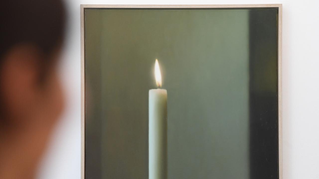 In einer Ausstellung hängt das Bild "Kerze" von Gerhard Richter, links davor sieht man verschwommen eine Frau, die das Bild betrachtet.