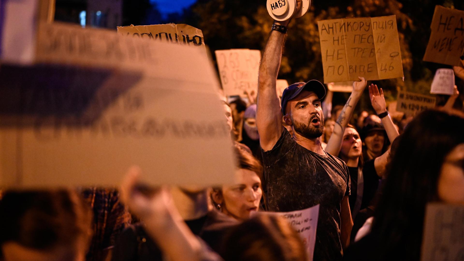 Menschen tragen Schilder und rufen etwas: In Kyiv demonstrieren Menschen gegen das neue Gesetz zur Einschränkung der Antikorruptionsbehörde.