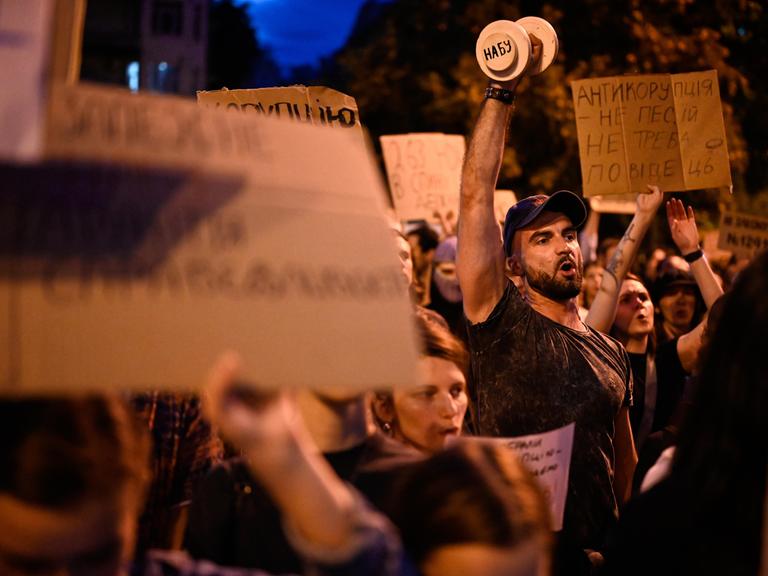 Menschen tragen Schilder und rufen etwas: In Kyiv demonstrieren Menschen gegen das neue Gesetz zur Einschränkung der Antikorruptionsbehörde.