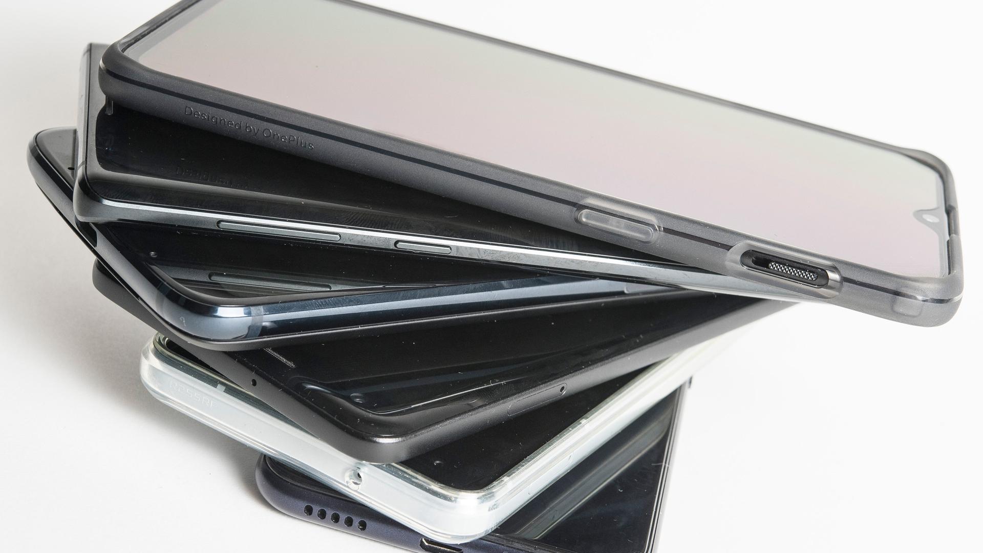 Gebrauchte Smartphones liegen gestapelt auf einem Tisch. Gebrauchte Smartphones liegen gestapelt auf einem Tisch.