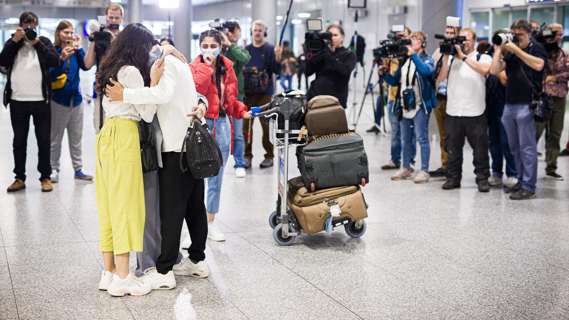 Menschen aus Afghanistan, die zuvor mit einem Flugzeug auf dem Flughafen Hannover gelandet sind, umarmen sich. Nach monatelanger Wartezeit sind mehrere Familien in Deutschland angekommen.