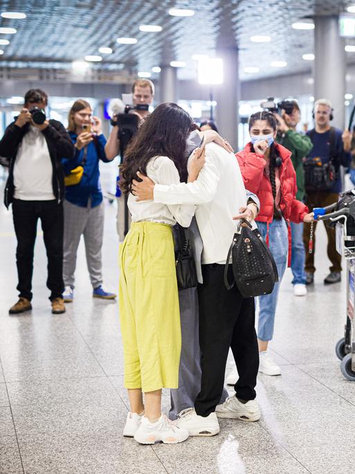 Menschen aus Afghanistan, die zuvor mit einem Flugzeug auf dem Flughafen Hannover gelandet sind, umarmen sich. Nach monatelanger Wartezeit sind mehrere Familien in Deutschland angekommen.