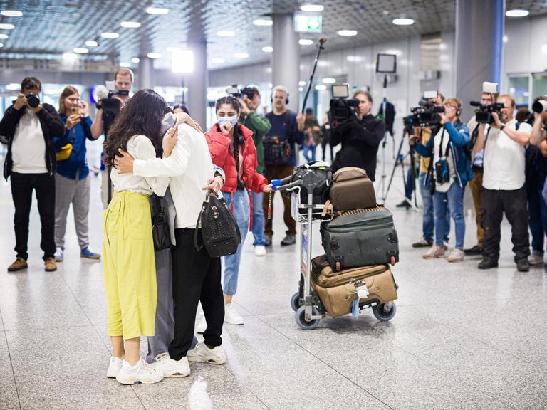 Menschen aus Afghanistan, die zuvor mit einem Flugzeug auf dem Flughafen Hannover gelandet sind, umarmen sich. Nach monatelanger Wartezeit sind mehrere Familien in Deutschland angekommen.