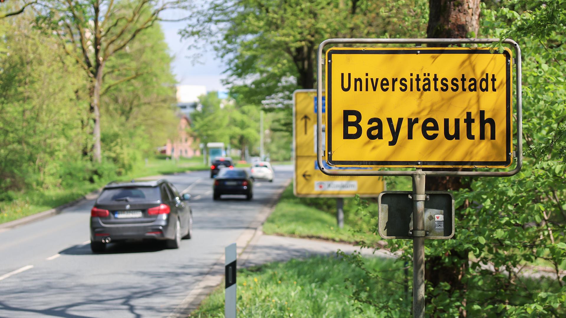 An einer Straße steht ein Ortsschild von Bayreuth. 