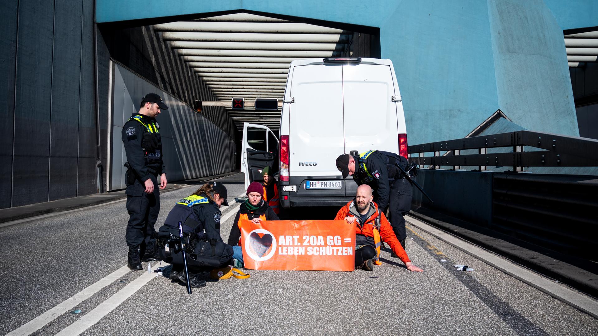 Klimaaktivisten haben sich auf der Fahrbahn der Autobahn 7 festgeklebt und blockieren so die Zufahrt des Elbtunnels in Richtung Norden.