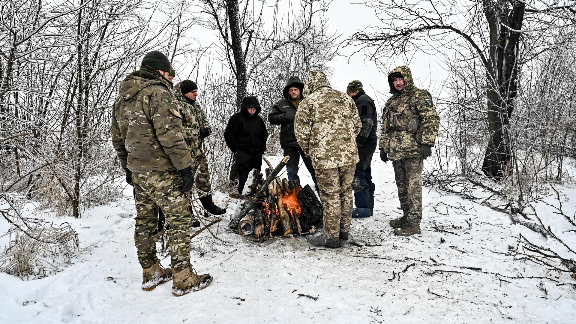 Soldaten der ukrainischen Streitkräfte im Südosten der Ukraine stehen um ein Feuer im Wald, 11. Januar 2024.