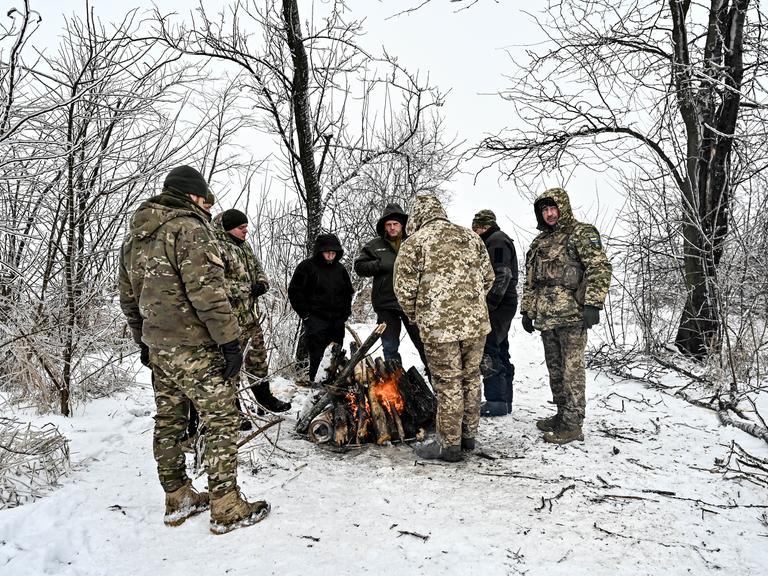 Soldaten der ukrainischen Streitkräfte im Südosten der Ukraine stehen um ein Feuer im Wald, 11. Januar 2024.