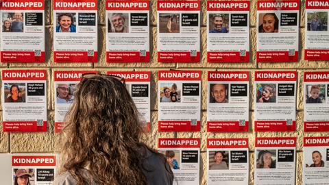 Eine Frau schaut auf Plakate, die Bilder der von der Hamas verschleppten Geiseln zeigen. Die Plakate tragen die Überschrift "Kidnapped", zu Deutsch: "Entführt".