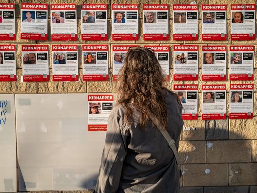 Eine Frau schaut in Tel-Aviv auf Plakate von Geiseln der Hamas.