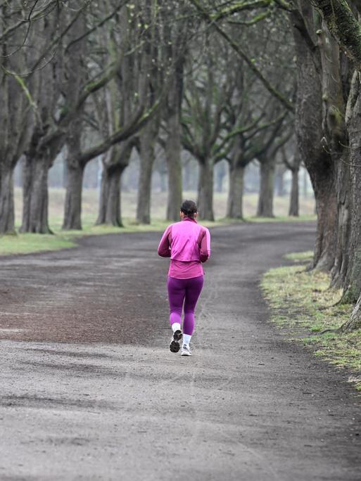 Eine Joggerin nutzt die Morgenstunden zu einem Lauf am Decksteiner Weiher durch die Kastanienallee (Köln).
