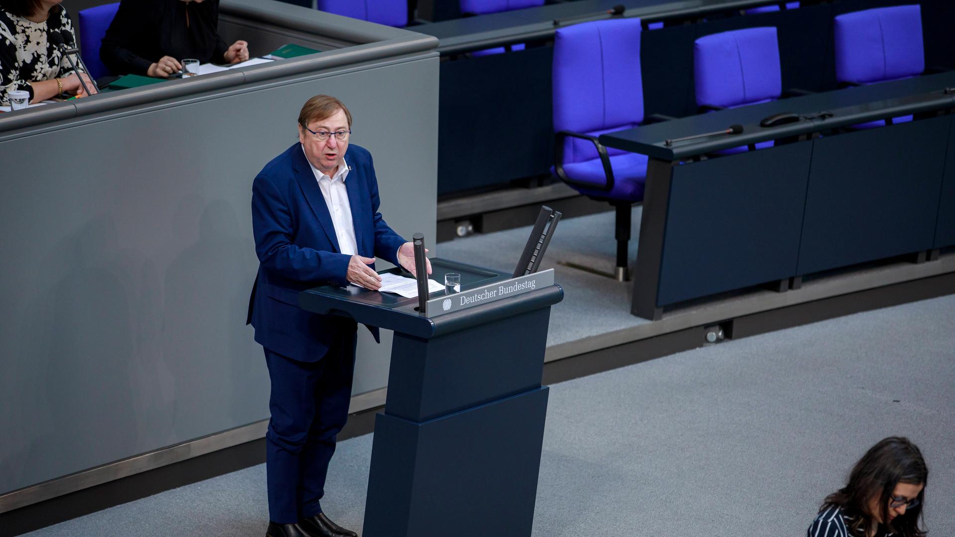 Linkenpolitiker André Hahn steht im blauen Anzug am Rednerpult im Bundestag.