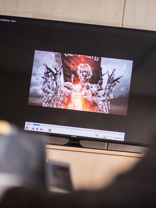 Auf einem Computerbildschirm ist eine Gruppe dschihadistischer Kämpfer in Uniform zu sehen. 